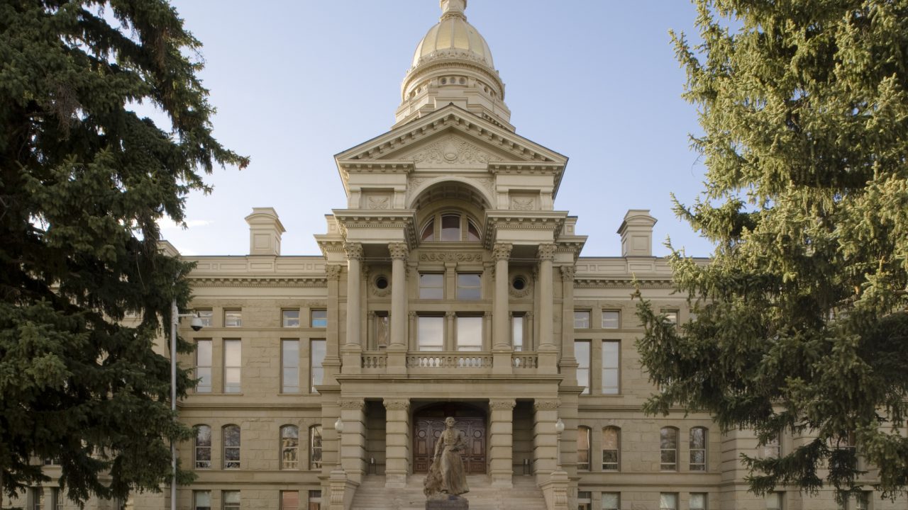 A view of the Wyoming State Capitol in Cheyenne. Designed by David W. Gibbs & Company and constructed between 1886 and 1890, the Renaissance Revival structure was enlarged with the addition of the House and Senate chambers in 1917. Built of sandstone and topped by a 146-foot tall, gold-leaf-covered dome, the Wyoming State Capitol is a National Historic Landmark. In the foreground is a statue of Esther Hobart Morris, who played a prominent role in granting women equal suffrage in Wyoming, the first territory to so provide such equal voting rights. A replica of the Morris statue, sculpted by Avard Fairbanks in 1958, stands in Statuary Hall of the United States Capitol.
