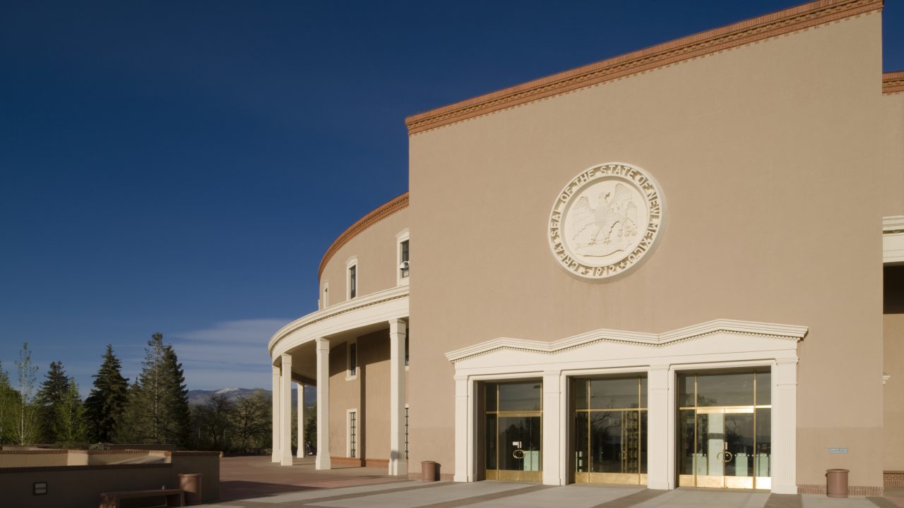A view of the New Mexico State Capitol, also known as the Roundhouse, in Santa Fe. Designed by W.C. Kruger and completed in 1966, the building, which incorporates traditional New Mexico territorial style elements, has a round shape inspired by the Zia sun symbol, which also appears in the state flag.