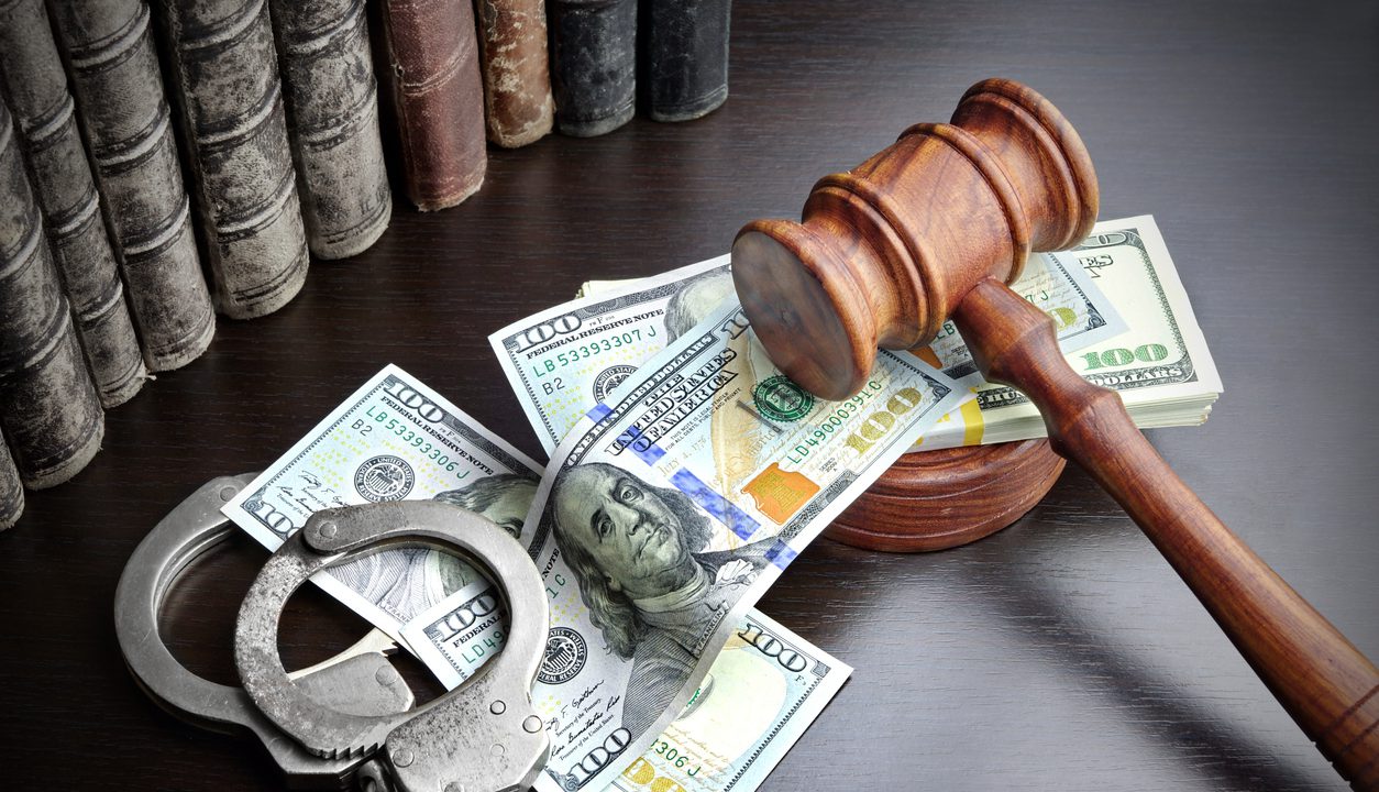 Judges Gavel, Handcuffs, Dollar Cash And Old Law Book On The Black Wooden Table Background In The Back Light. Overhead View.
