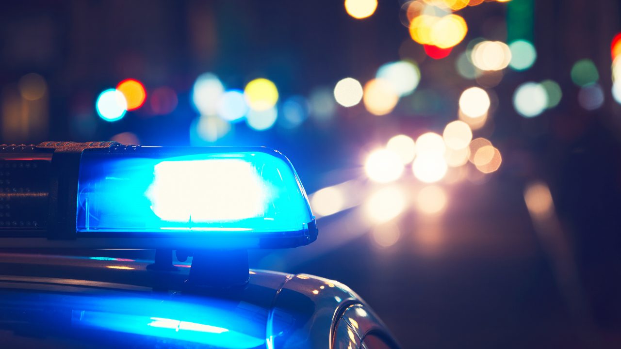 Danger on the road. Blue flasher on the police car at night.