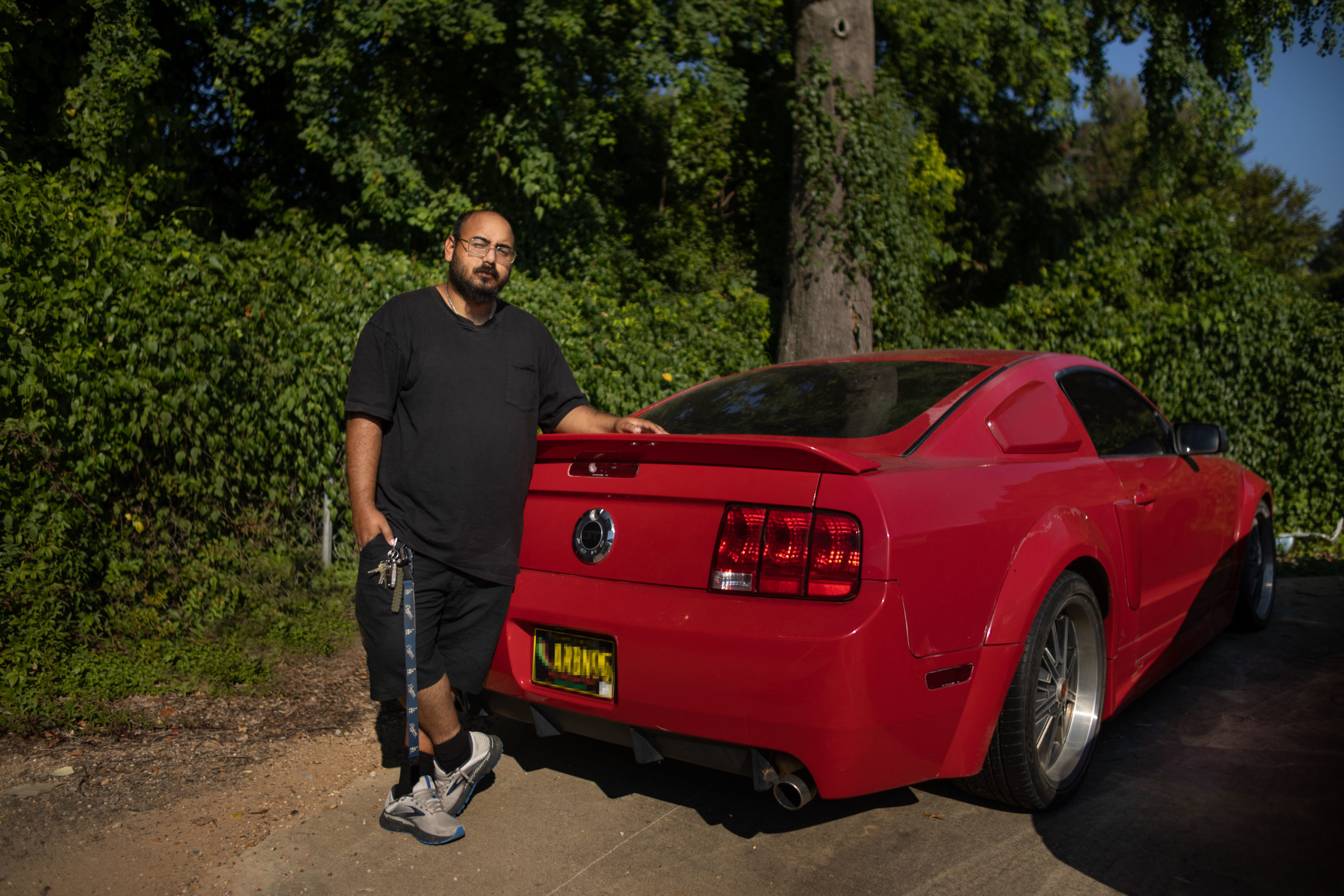 man standing behind red sports car