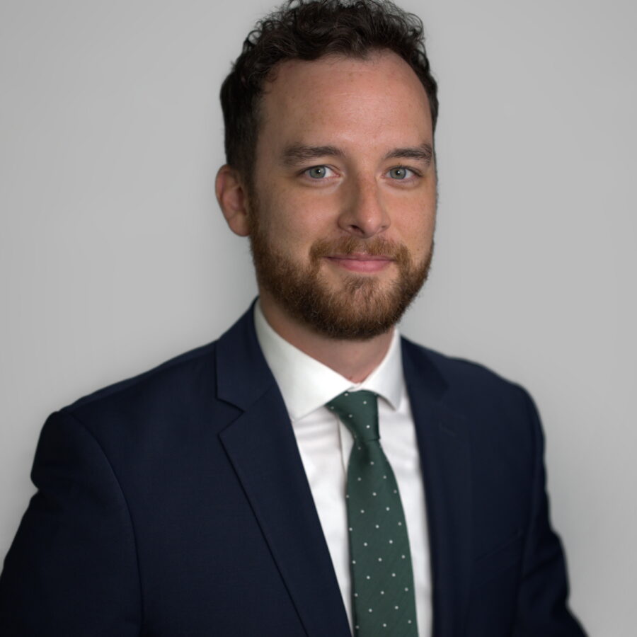 Man with beard in navy suit and green polka-dot tie, professional headshot portrait