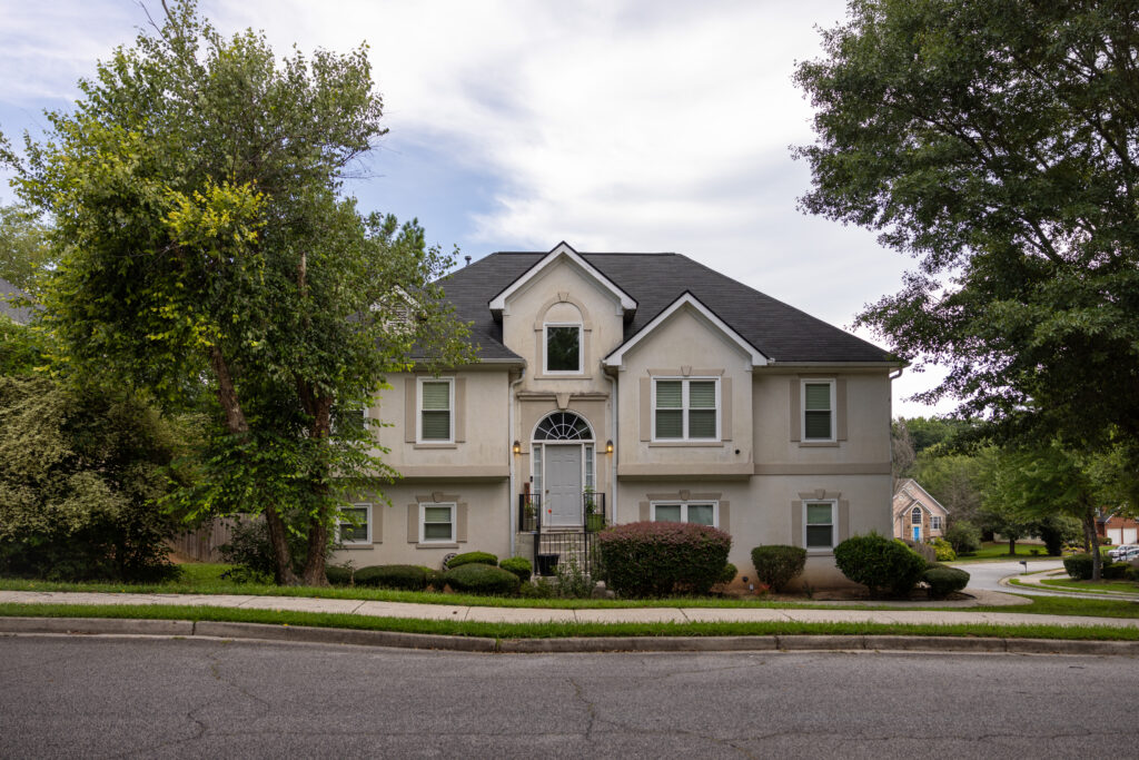 Two-story stucco suburban house with dark roof, the residence FBI had a warrant to raid