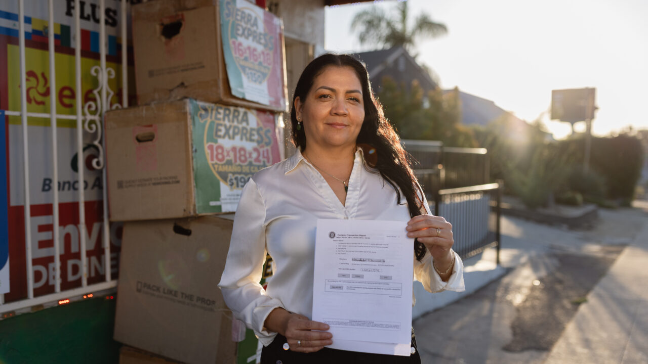 Esperanza Gomez holds a Currency Transaction Report outside her money-transfer business storefront