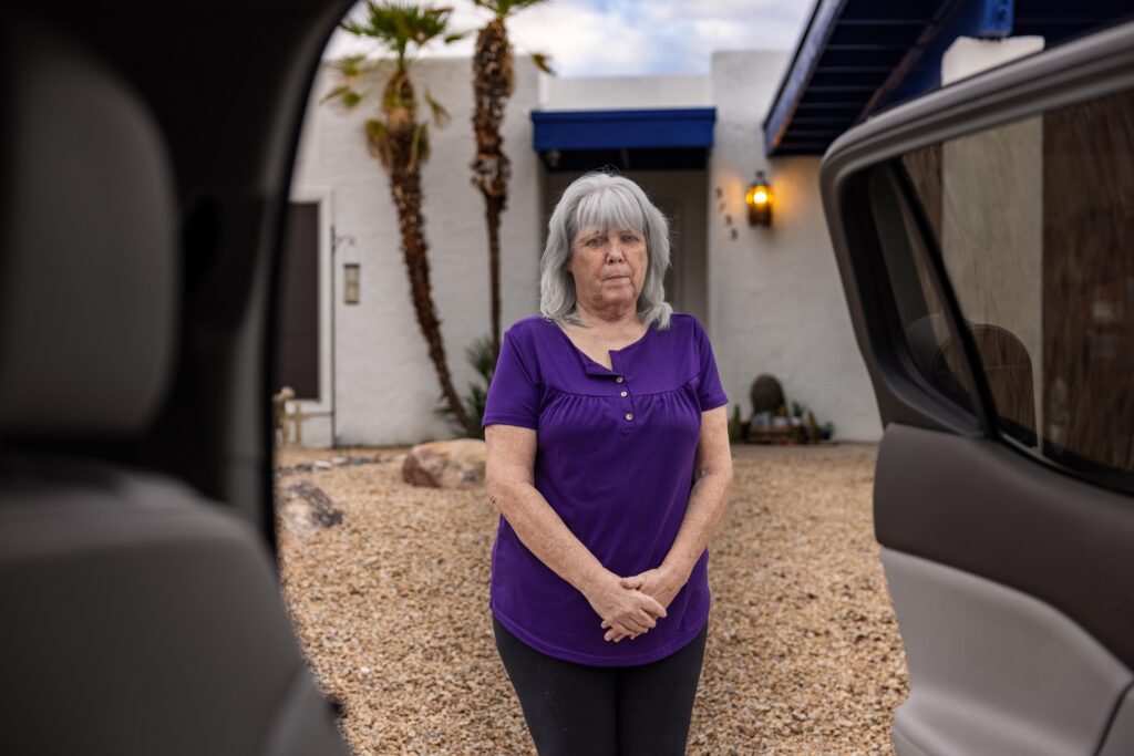 woman standing in front of home and see through car doors