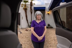 woman standing in front of home and see through car doors