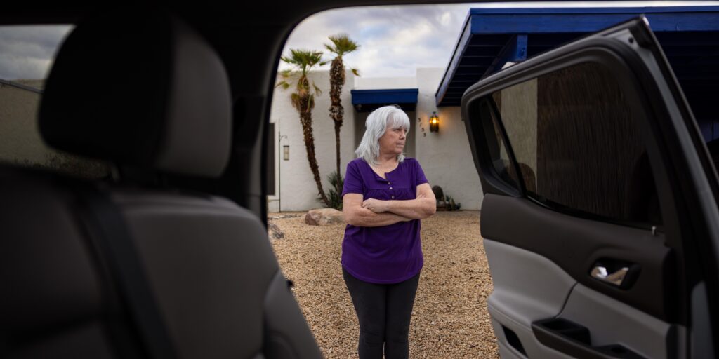woman standing in front of home and see through car doors