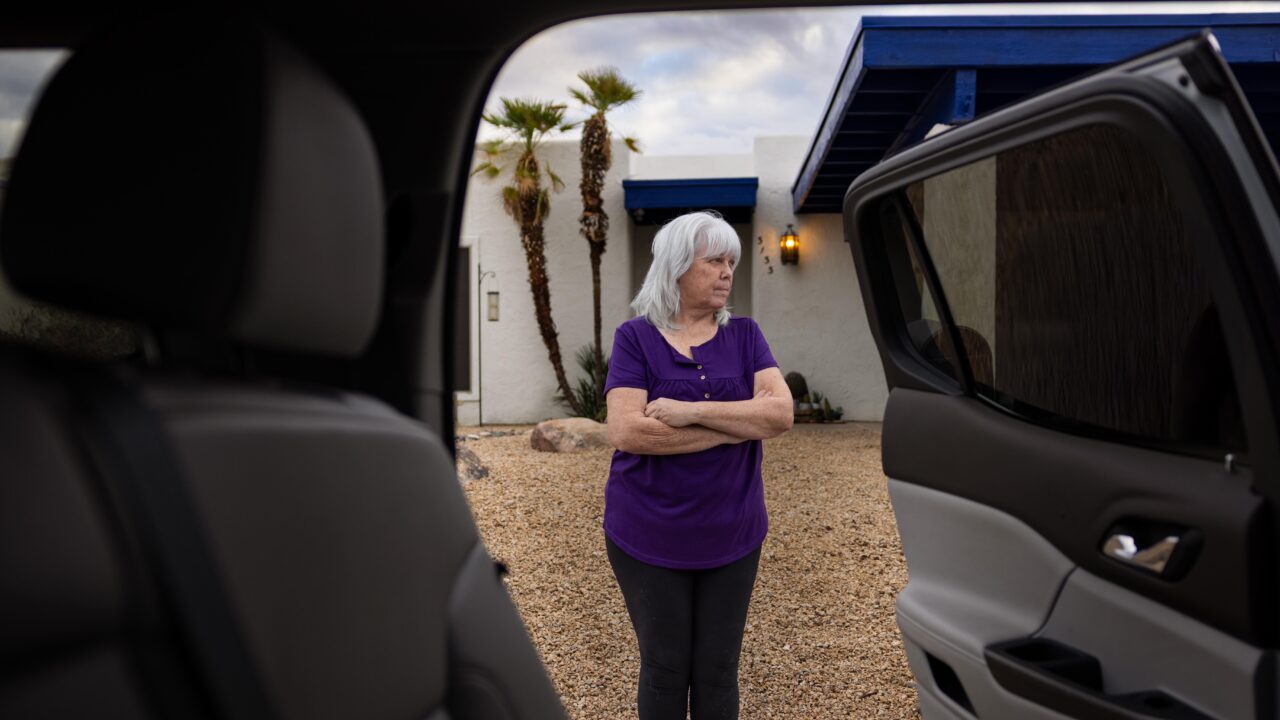 woman standing in front of home and see through car doors