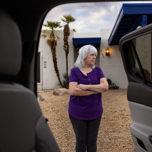 woman standing in front of home and see through car doors
