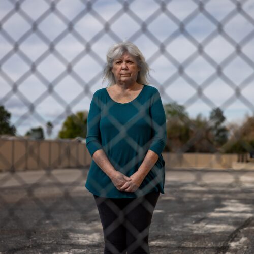 woman stands behind chain link fence