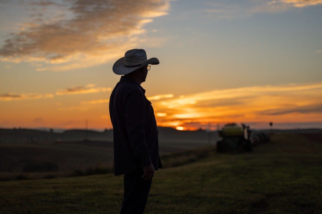 rancher wearing cowboy hat with sun rising