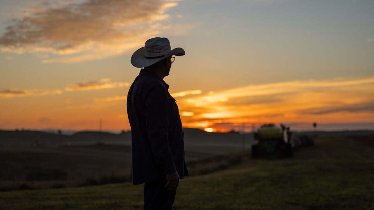 rancher wearing cowboy hat with sun rising
