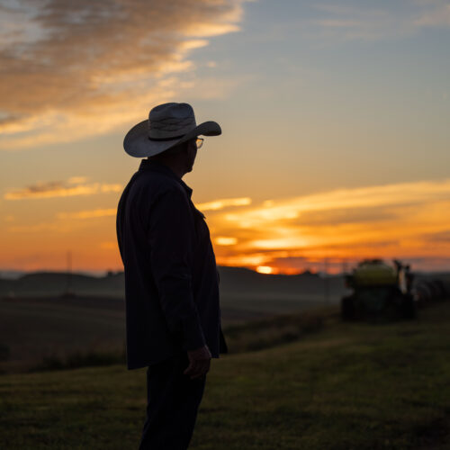rancher wearing cowboy hat with sun rising