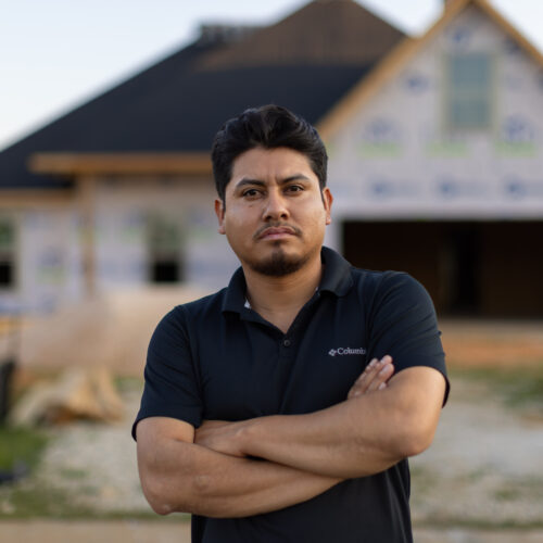construction worker in front of partially built home