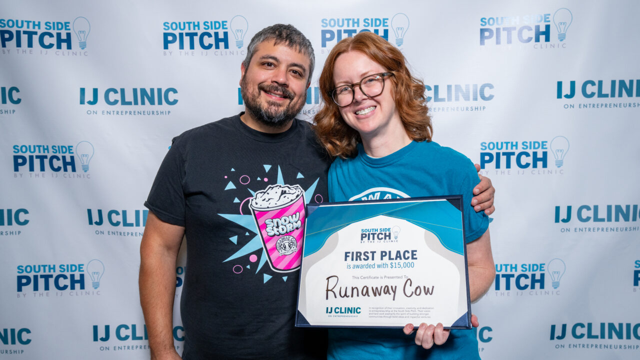 Two people smiling, holding a South Side Pitch first place certificate for Runaway Cow