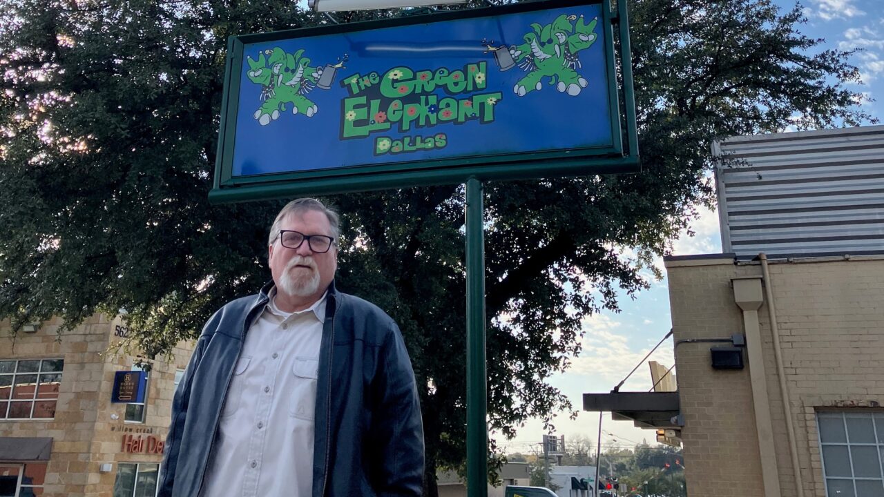 Shannon McKinnon stands beneath The Green Elephant Dallas sign outside the bar