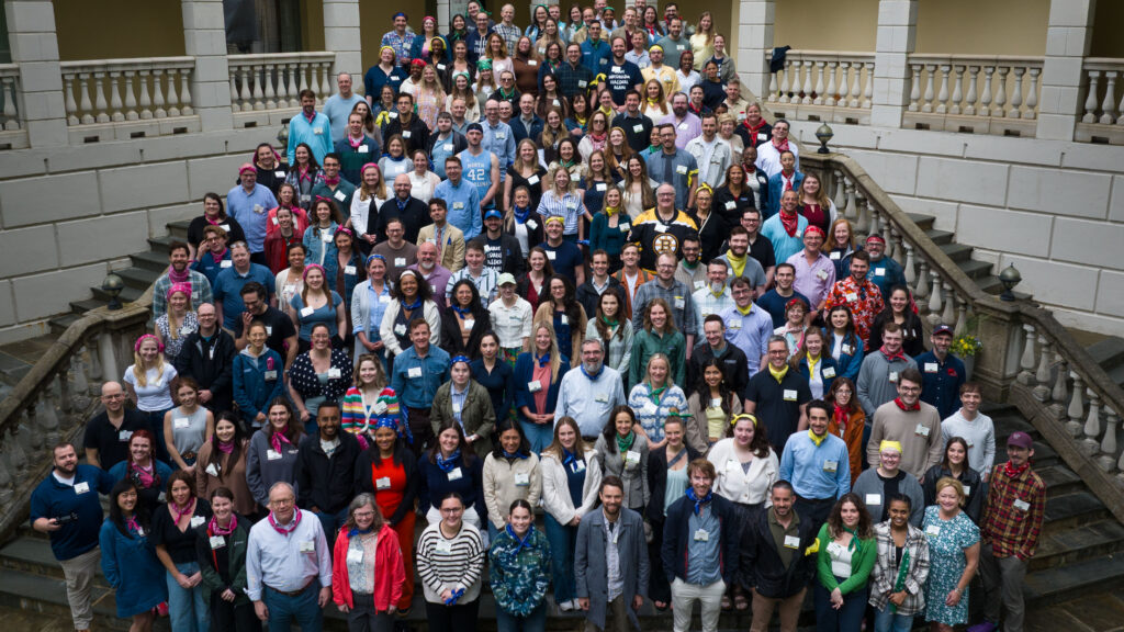 Large group of people wearing name tags standing on stone steps with white columns and balustrades