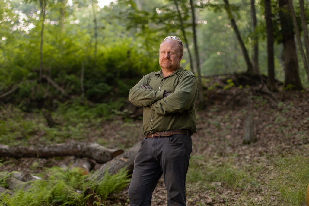 Charles Copley stands arms crossed on his wooded property in Roxbury, Connecticut