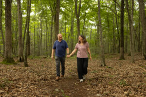Charles and Eli Copley hold hands walking a wooded trail on their Roxbury, Connecticut property