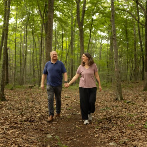 Charles and Eli Copley hold hands walking a wooded trail on their Roxbury, Connecticut property