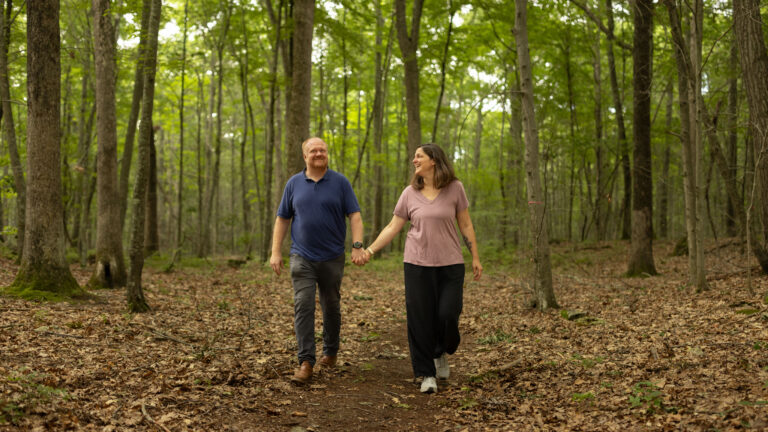 Charles and Eli Copley hold hands walking a wooded trail on their Roxbury, Connecticut property