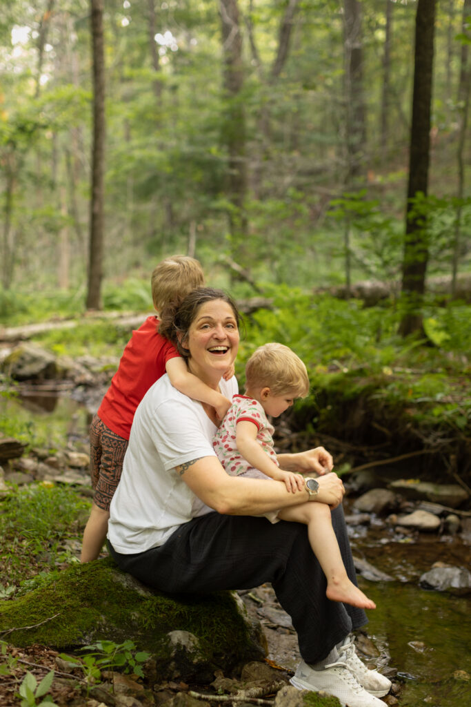 Eli Copley laughs with her children by a wooded stream on her Roxbury, Connecticut property