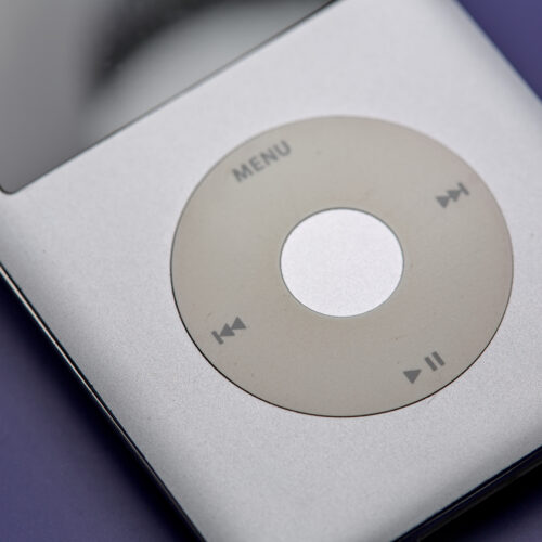 Silver iPod with circular click wheel showing menu and playback controls, with screen visible at top