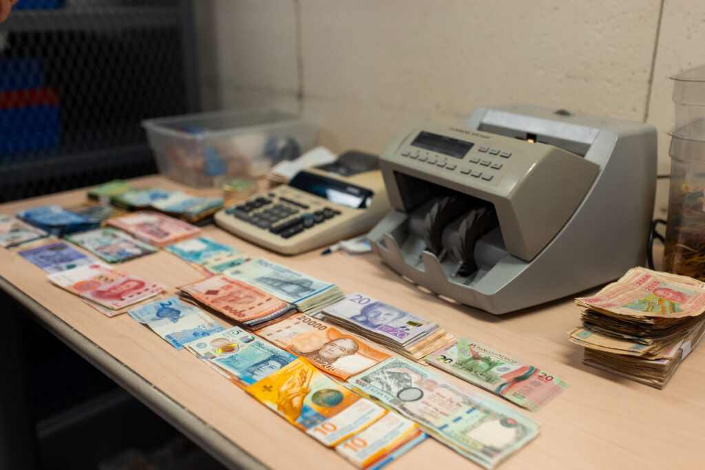 Foreign currency bills, a money counter, and adding machine on a table in a vault