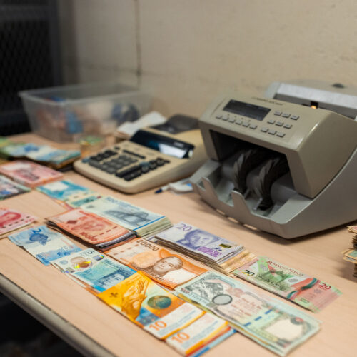 Foreign currency bills, a money counter, and adding machine on a table in a vault