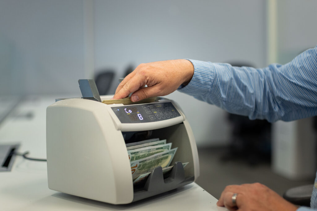 Steven Bailey puts money through a bill-counting machine at Global Coin Logistics'' office in Louisville, Kentucky.