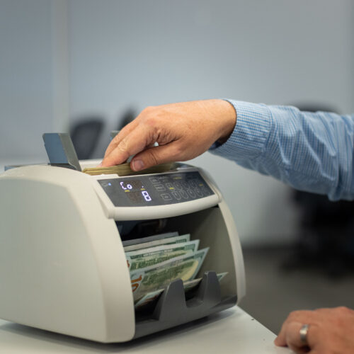 Steven Bailey puts money through a bill-counting machine at Global Coin Logistics'' office in Louisville, Kentucky.