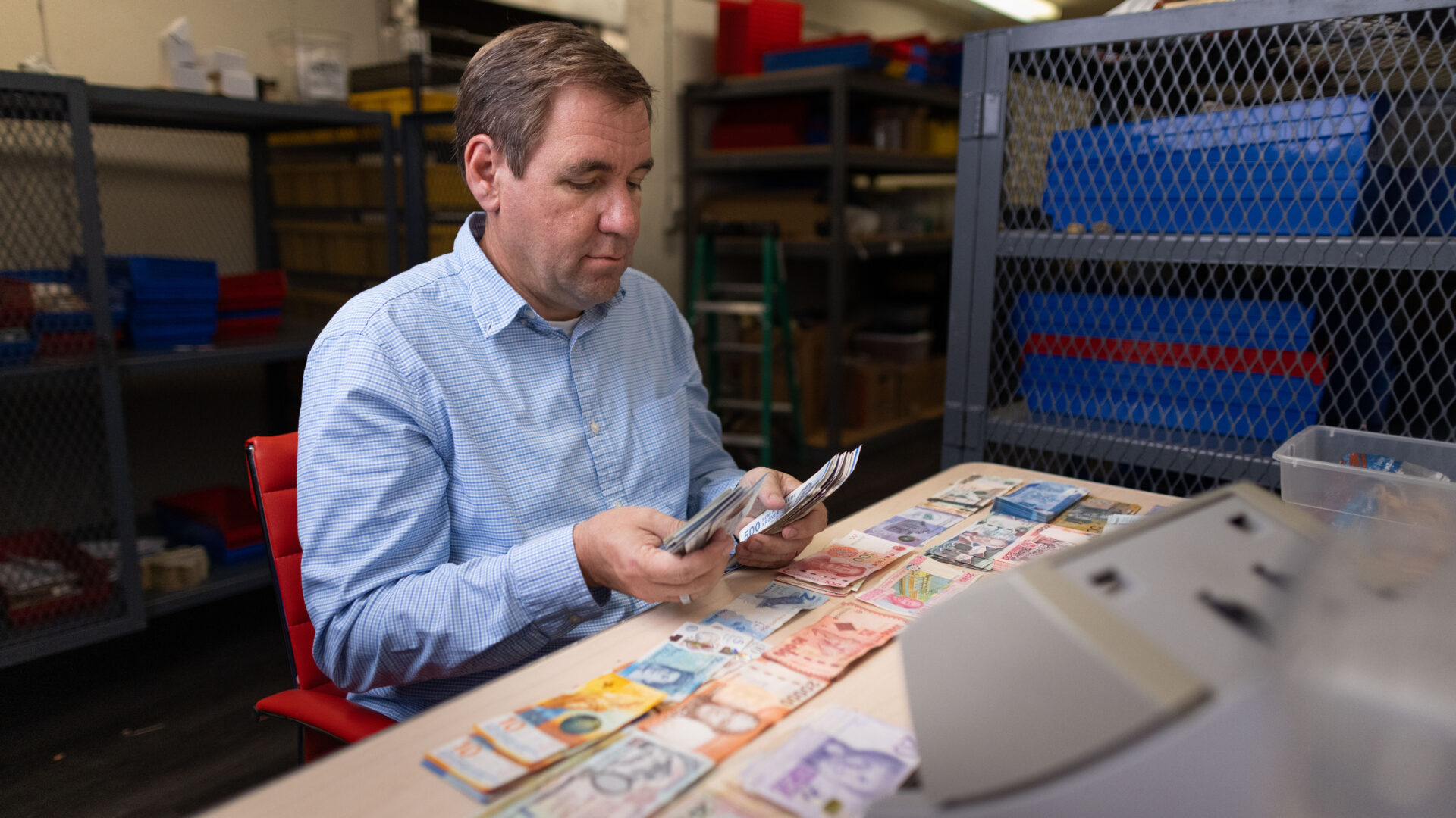 Steven Bailey sorting various foreign currency bills inside Global Coin Logistics' vault in Louisville, Kentucky.