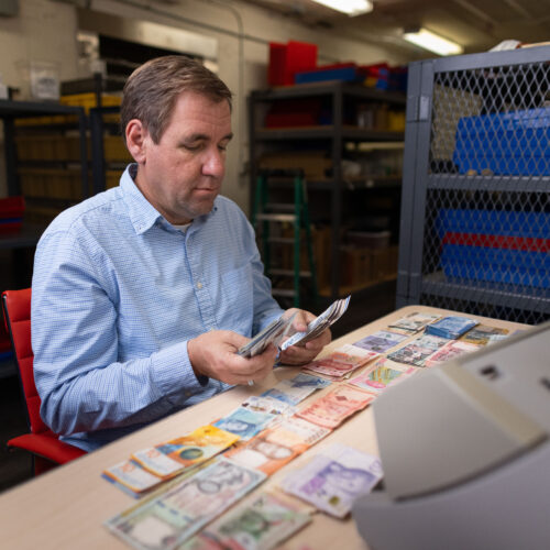 Steven Bailey sorting various foreign currency bills inside Global Coin Logistics' vault in Louisville, Kentucky.
