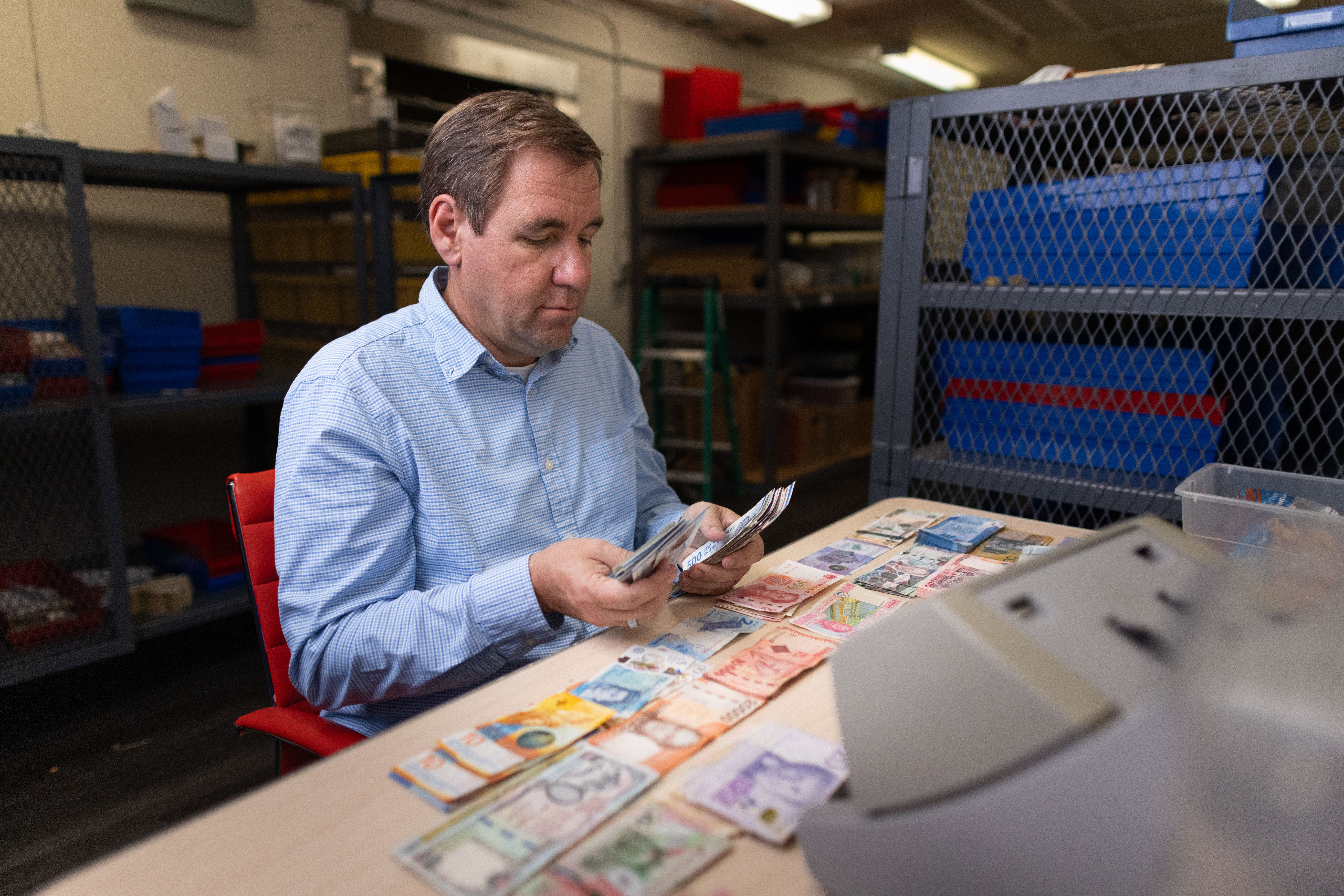 Steven Bailey sorting various foreign currency bills inside Global Coin Logistics' vault in Louisville, Kentucky.