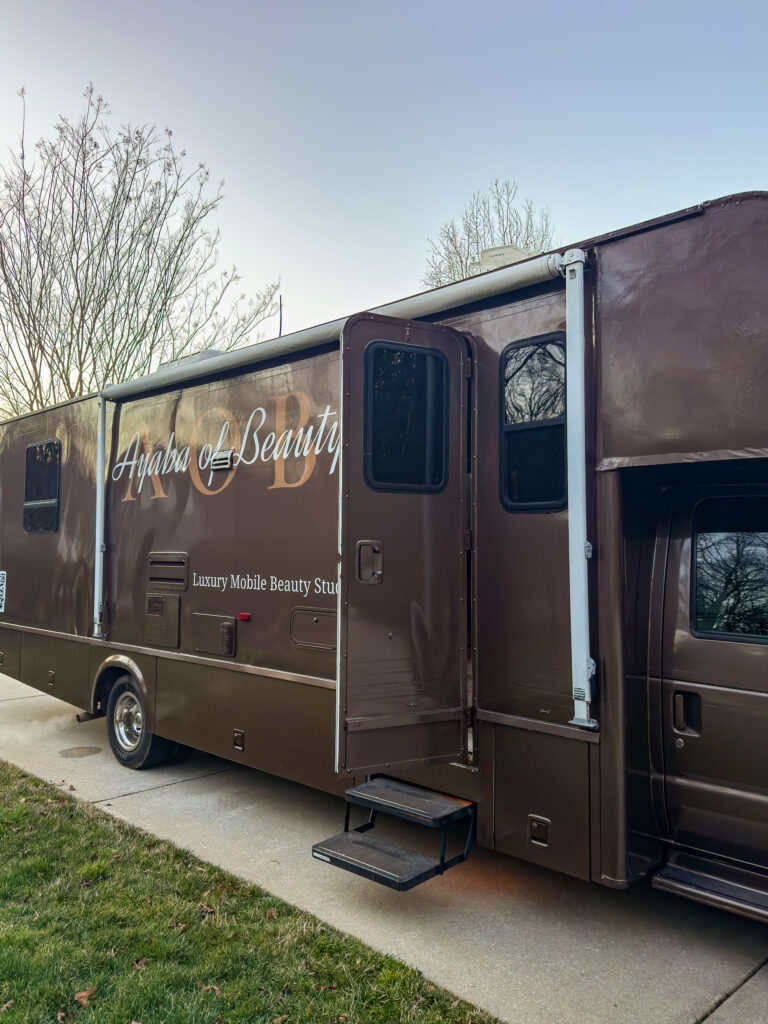 Brown RV with open door reading Ayaba of Beauty Luxury Mobile Beauty Studio