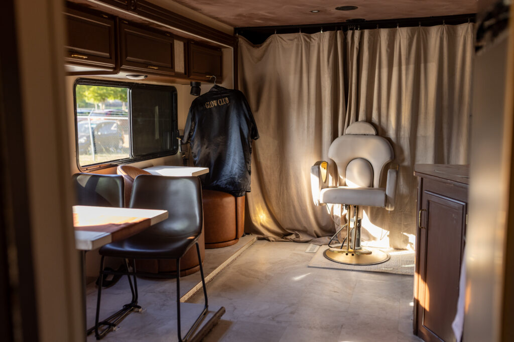 Interior of mobile salon trailer with white styling chair and Glow Club robe hanging
