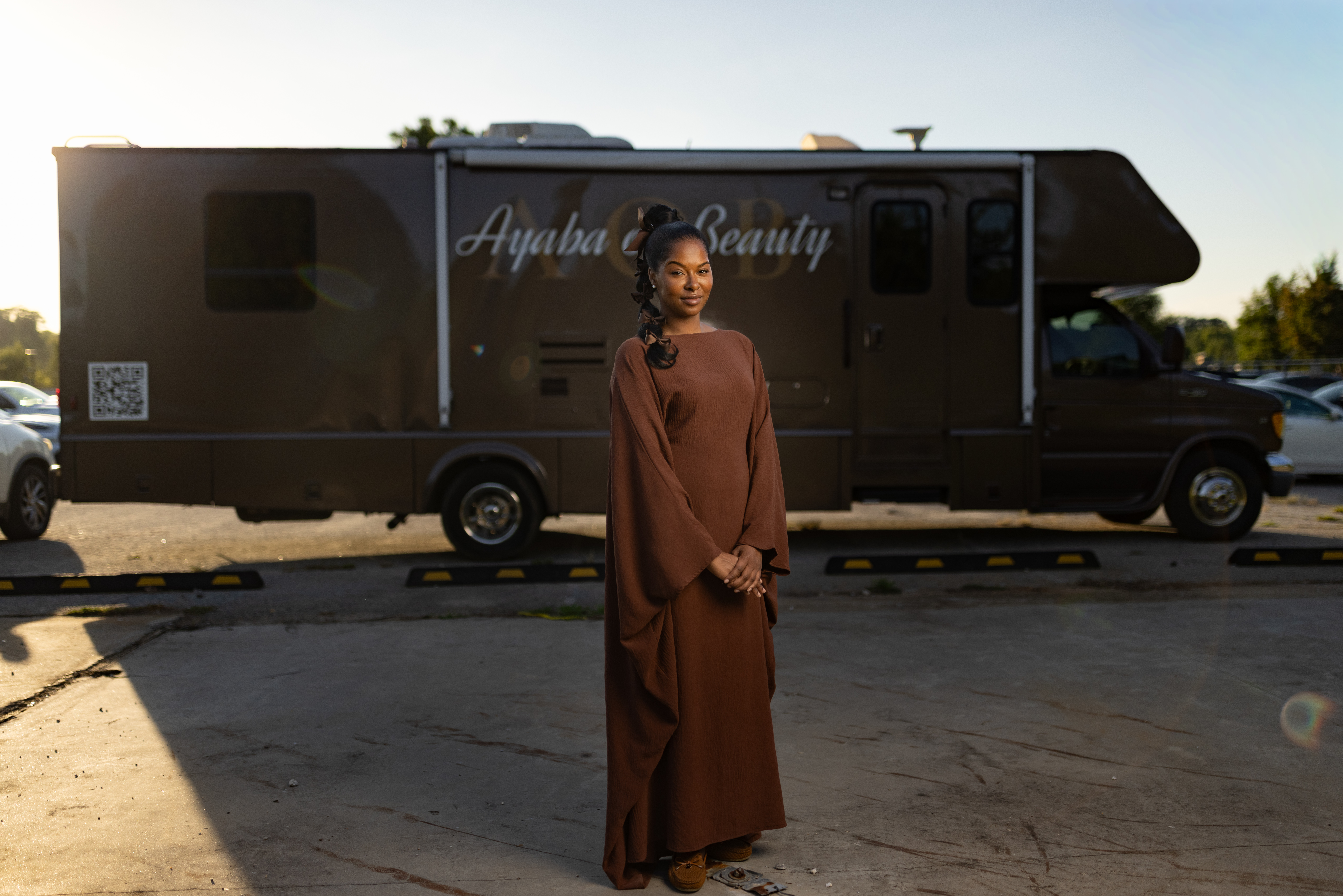 Woman standing in front of the Ayaba Beauty mobile salon RV in a parking lot