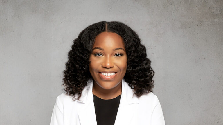 Woman with curly hair smiling in white blazer, professional headshot for Vash Beauty Labs