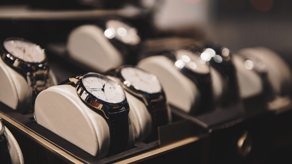 Rows of wristwatches with round faces displayed on cushions in a store case