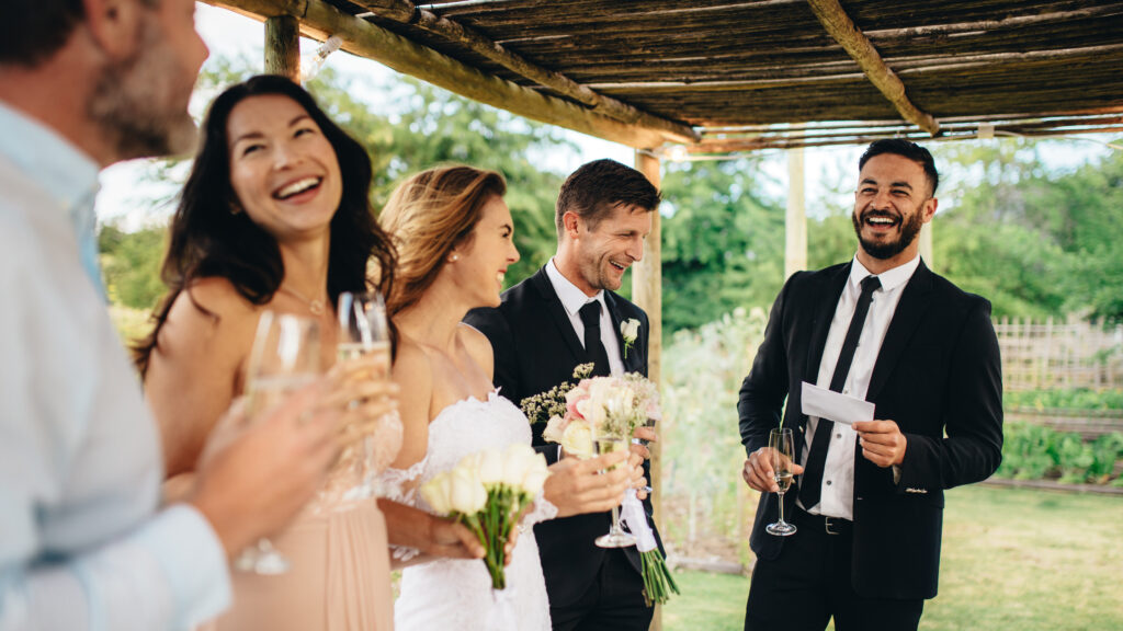 Best man gives speech to bride and groom during outdoor wedding reception toast