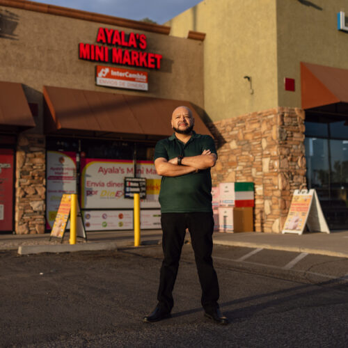 Mario Ayala stands arms crossed outside Ayala's Mini Market storefront in Glendale, Arizona.