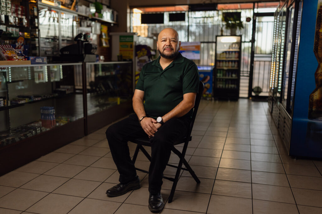 Mario Ayala sits on a chair inside Ayala's Mini Market, his convenience store in Glendale, Arizona.