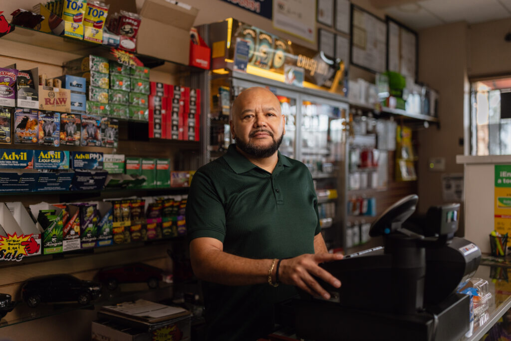 Mario Ayala stands behind the counter at Ayala's Mini Market in Glendale, Arizona.