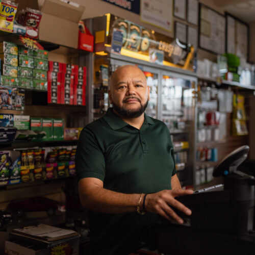 Mario Ayala stands behind the counter at Ayala's Mini Market in Glendale, Arizona.