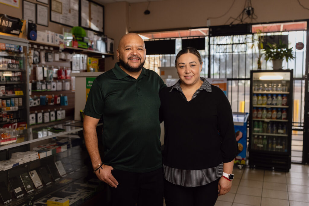 Man and woman standing together inside a convenience store with phone accessories and drink cooler