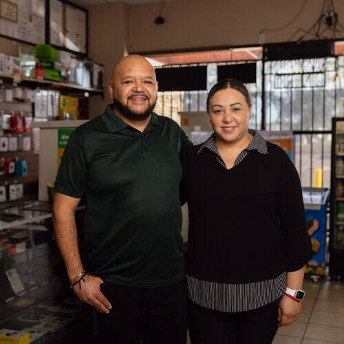 Man and woman standing together inside a convenience store with phone accessories and drink cooler