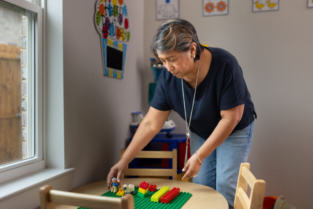 Rosi Paredes arranges building blocks and toys on a table in her home daycare