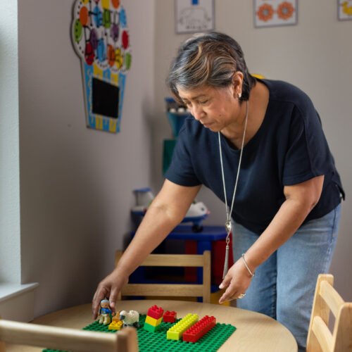 Rosi Paredes arranges building blocks and toys on a table in her home daycare