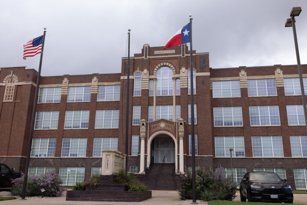 Brick former high school building, now Johnson County Courthouse, with American and Texas flags