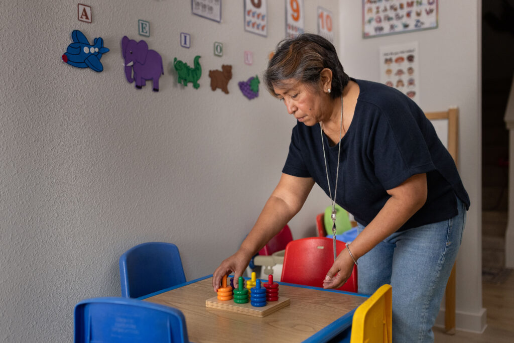 Rosi Paredes arranges a stacking toy at a child's table in her home daycare